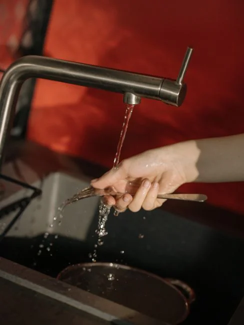 A person in protective gear sanitizing an office desk using fumigation equipment during daytime.